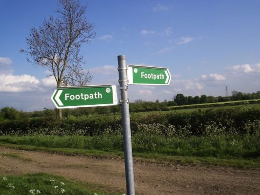 Two fingerpost signs, each saying footpath, in the countryside